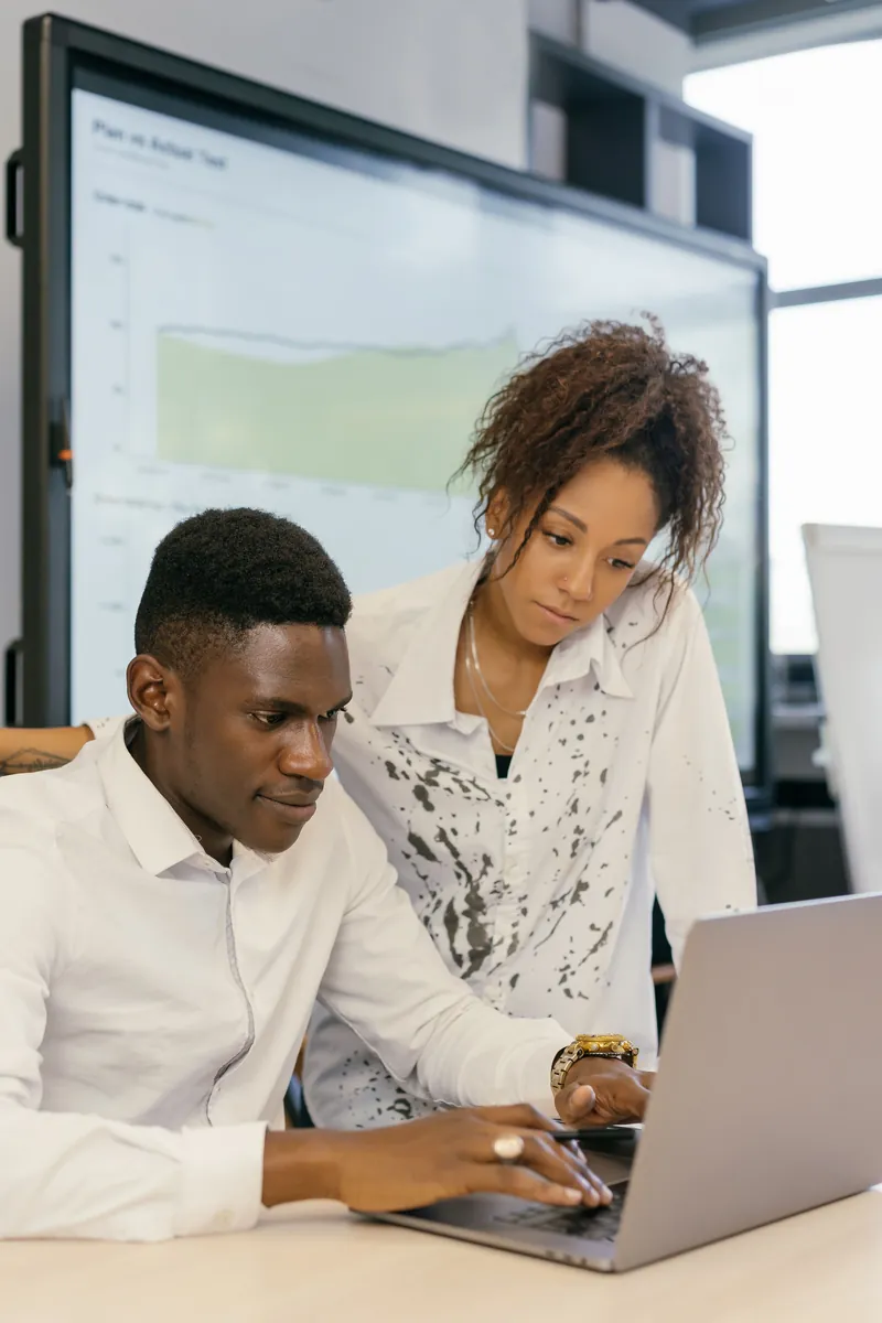 Two colleagues working through a task at a laptop
