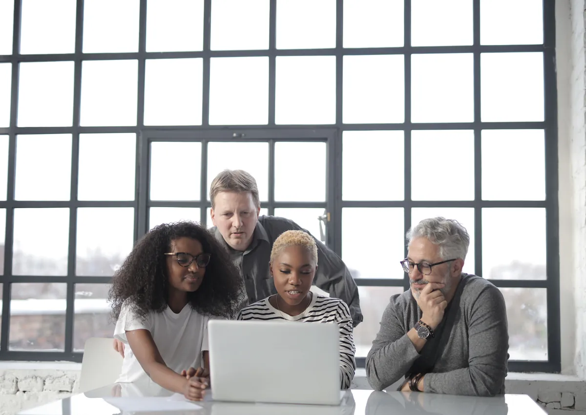 A small team reviewing work together on a laptop